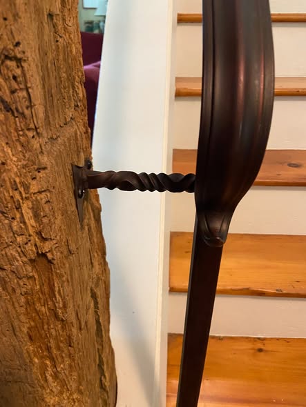 Close detail of a twisted metal railing bracket fixed to a timber post